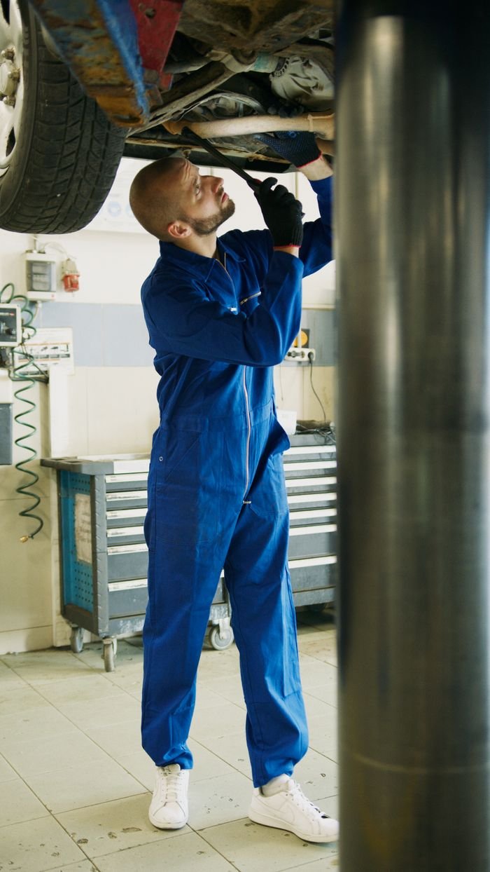 A skilled mechanic works on car maintenance in a professional garage setting.
